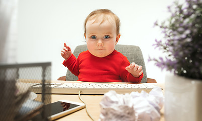 Image showing Happy child baby girl toddler sitting with keyboard of computer isolated on a white background