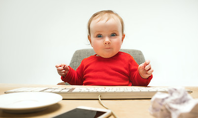 Image showing Happy child baby girl toddler sitting with keyboard of computer isolated on a white background