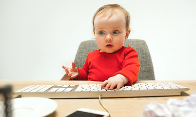 Image showing Happy child baby girl toddler sitting with keyboard of computer isolated on a white background