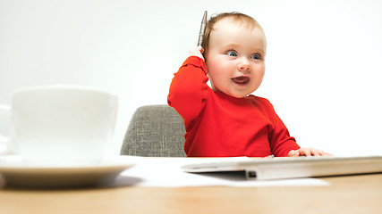 Image showing Happy child baby girl toddler sitting with keyboard of computer isolated on a white background