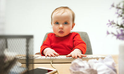 Image showing Happy child baby girl toddler sitting with keyboard of computer isolated on a white background