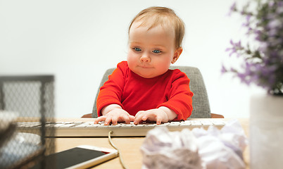 Image showing Happy child baby girl toddler sitting with keyboard of computer isolated on a white background