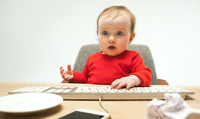 Image showing Happy child baby girl toddler sitting with keyboard of computer isolated on a white background