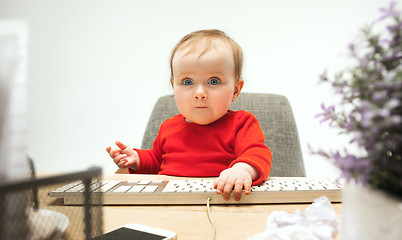 Image showing Happy child baby girl toddler sitting with keyboard of computer isolated on a white background