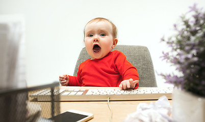 Image showing Happy child baby girl toddler sitting with keyboard of computer isolated on a white background