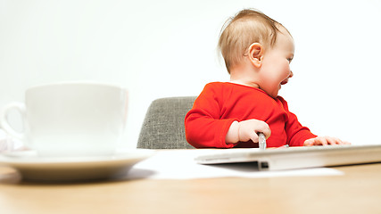 Image showing Happy child baby girl toddler sitting with keyboard of computer isolated on a white background