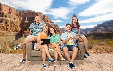 Image showing friends with tablet pc and smartphones sit on sofa