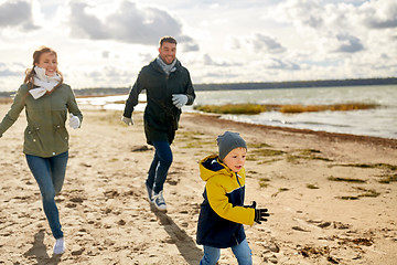 Image showing happy family running along autumn beach