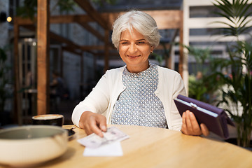 Image showing senior woman with money paying bill at cafe