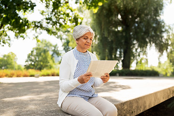 Image showing senior woman reading newspaper at summer park