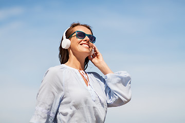 Image showing woman with headphones over blue sky