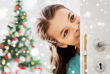 Image showing happy girl looking out open door on christmas