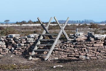 Image showing Old wooden stile by a stone wall