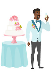 Image showing Groom standing near cake with glass of champagne.