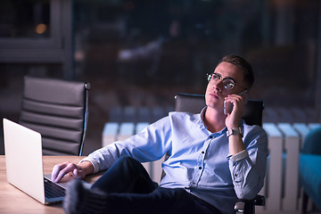 Image showing businessman using mobile phone in dark office