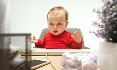 Image showing Happy child baby girl toddler sitting with keyboard of computer isolated on a white background