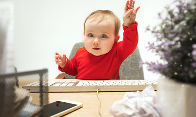 Image showing Happy child baby girl toddler sitting with keyboard of computer isolated on a white background