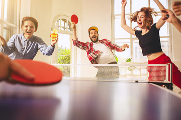 Image showing Group of happy young friends playing ping pong table tennis