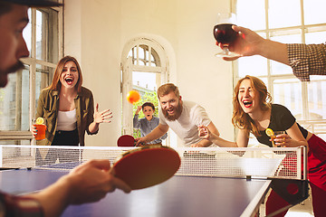 Image showing Group of happy young friends playing ping pong table tennis