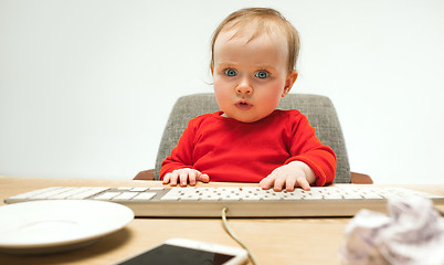 Image showing Happy child baby girl toddler sitting with keyboard of computer isolated on a white background