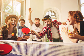 Image showing Group of happy young friends playing ping pong table tennis