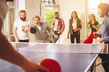 Image showing Group of happy young friends playing ping pong table tennis