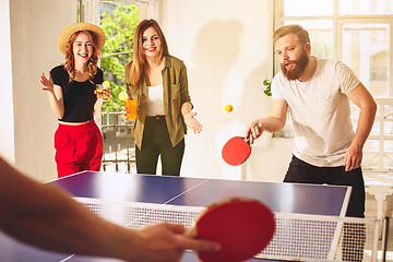 Image showing Group of happy young friends playing ping pong table tennis