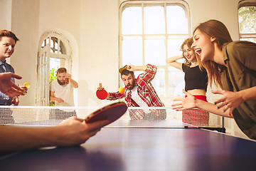 Image showing Group of happy young friends playing ping pong table tennis