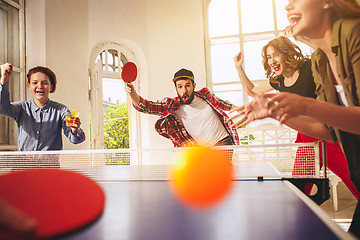 Image showing Group of happy young friends playing ping pong table tennis