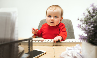 Image showing Happy child baby girl toddler sitting with keyboard of computer isolated on a white background