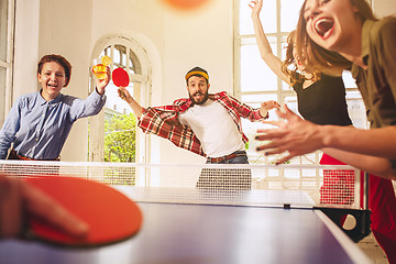 Image showing Group of happy young friends playing ping pong table tennis