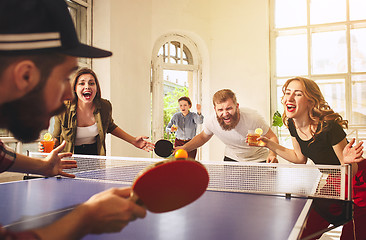 Image showing Group of happy young friends playing ping pong table tennis