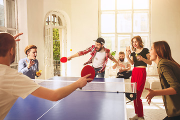 Image showing Group of happy young friends playing ping pong table tennis