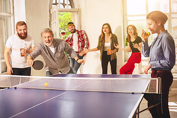 Image showing Group of happy young friends playing ping pong table tennis