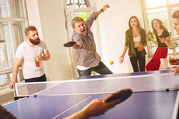 Image showing Group of happy young friends playing ping pong table tennis