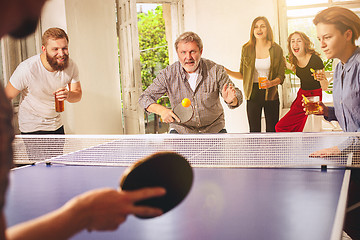 Image showing Group of happy young friends playing ping pong table tennis