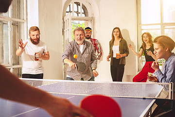 Image showing Group of happy young friends playing ping pong table tennis