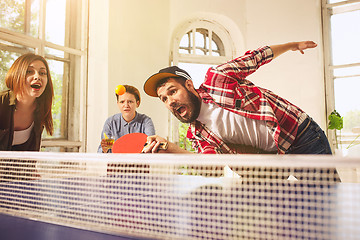 Image showing Group of happy young friends playing ping pong table tennis