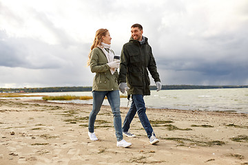 Image showing couple with tumbler walking along autumn beach