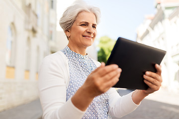 Image showing smiling senior woman with tablet pc on city street