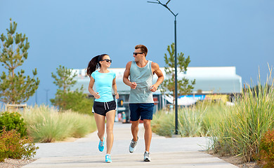 Image showing couple in sports clothes running along beach path