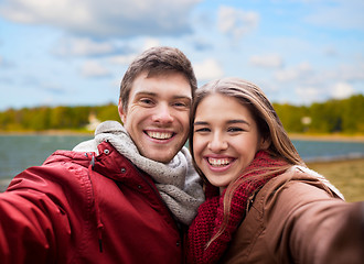 Image showing happy young couple taking selfie on autumn beach