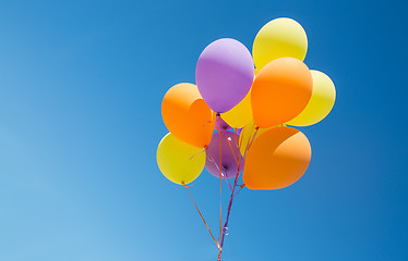 Image showing close up of colorful helium balloons in blue sky