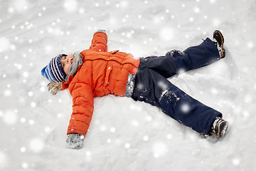 Image showing happy little boy making snow angels in winter