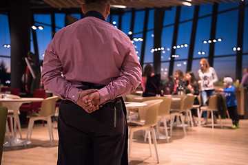 Image showing waiter standing with hands behind his back