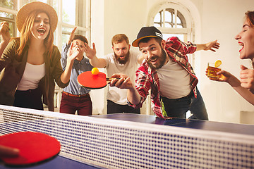 Image showing Group of happy young friends playing ping pong table tennis