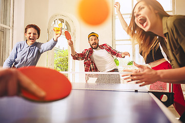 Image showing Group of happy young friends playing ping pong table tennis