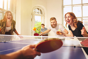 Image showing Group of happy young friends playing ping pong table tennis