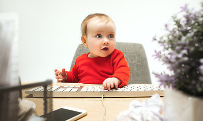 Image showing Happy child baby girl toddler sitting with keyboard of computer isolated on a white background