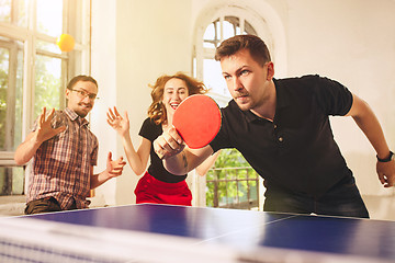 Image showing Group of happy young friends playing ping pong table tennis